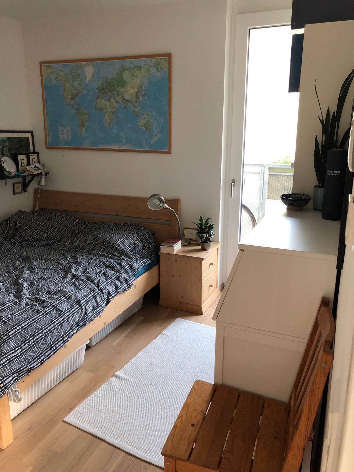 Schlafzimmer mit Holzbett, Nachttisch und Zugang zu einem Außenbereich.