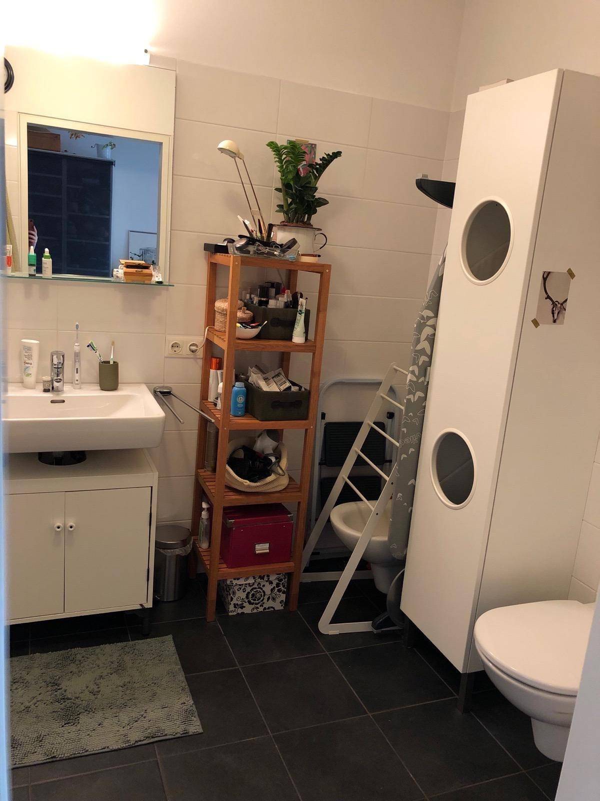 Badezimmer mit Waschbecken, Toilette und dunklen Bodenfliesen.