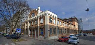 Klassisches Eckgebäude mit historischer Fassade und vielen Fenstern an einer belebten Stadtstraße.