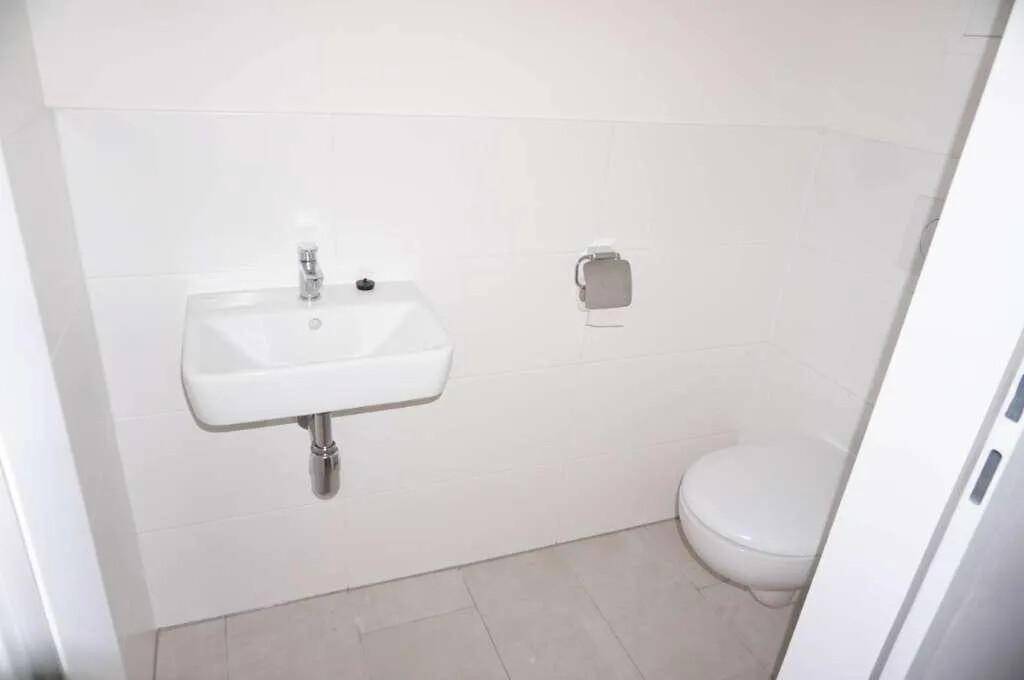 Modernes Gäste-WC mit wandmontiertem Waschbecken und Toilette in hellem Design.