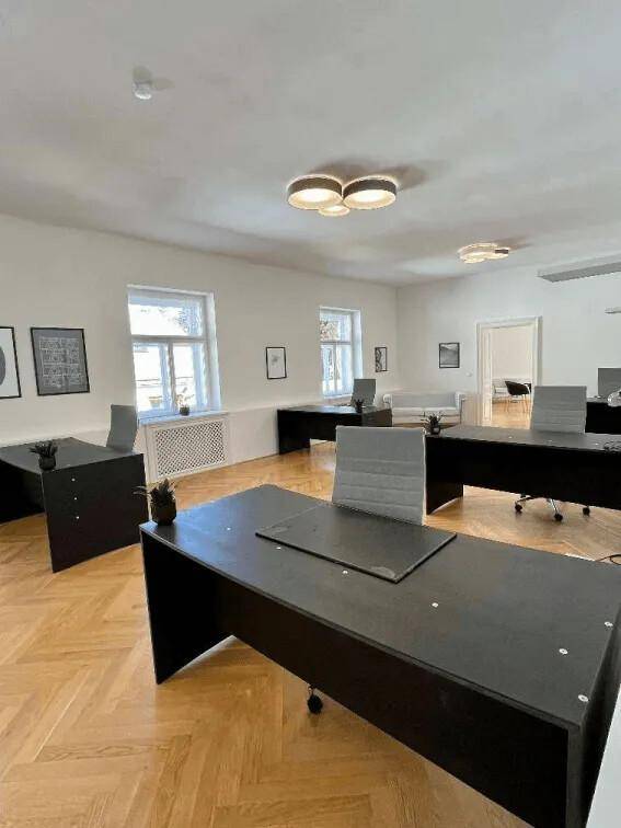 Großes, helles Büro mit mehreren modernen Arbeitsplätzen, Fischgrätparkett und Deckenleuchten.