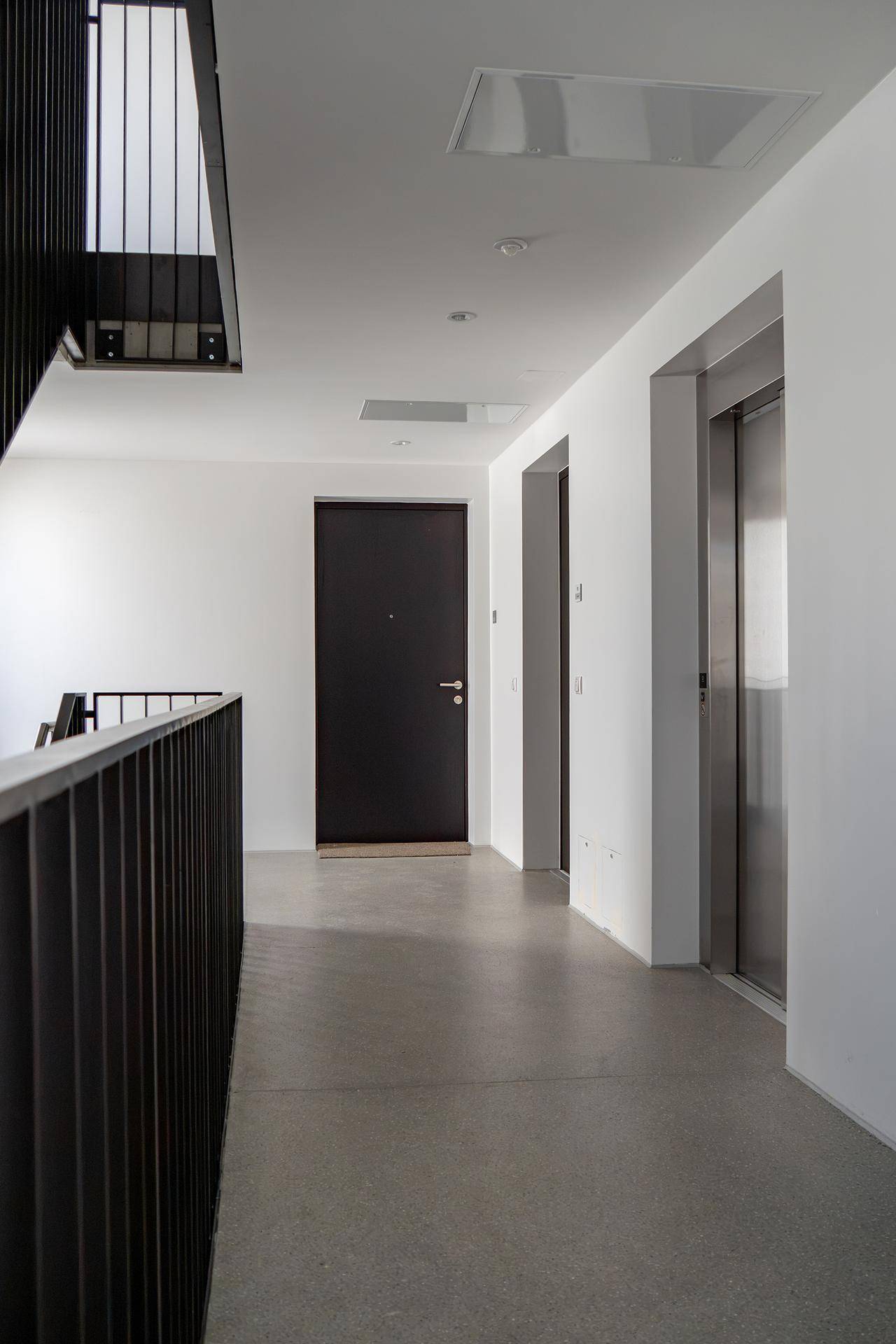 Heller Flur mit Aufzug und modernen Türen in einem Mehrfamilienhaus.