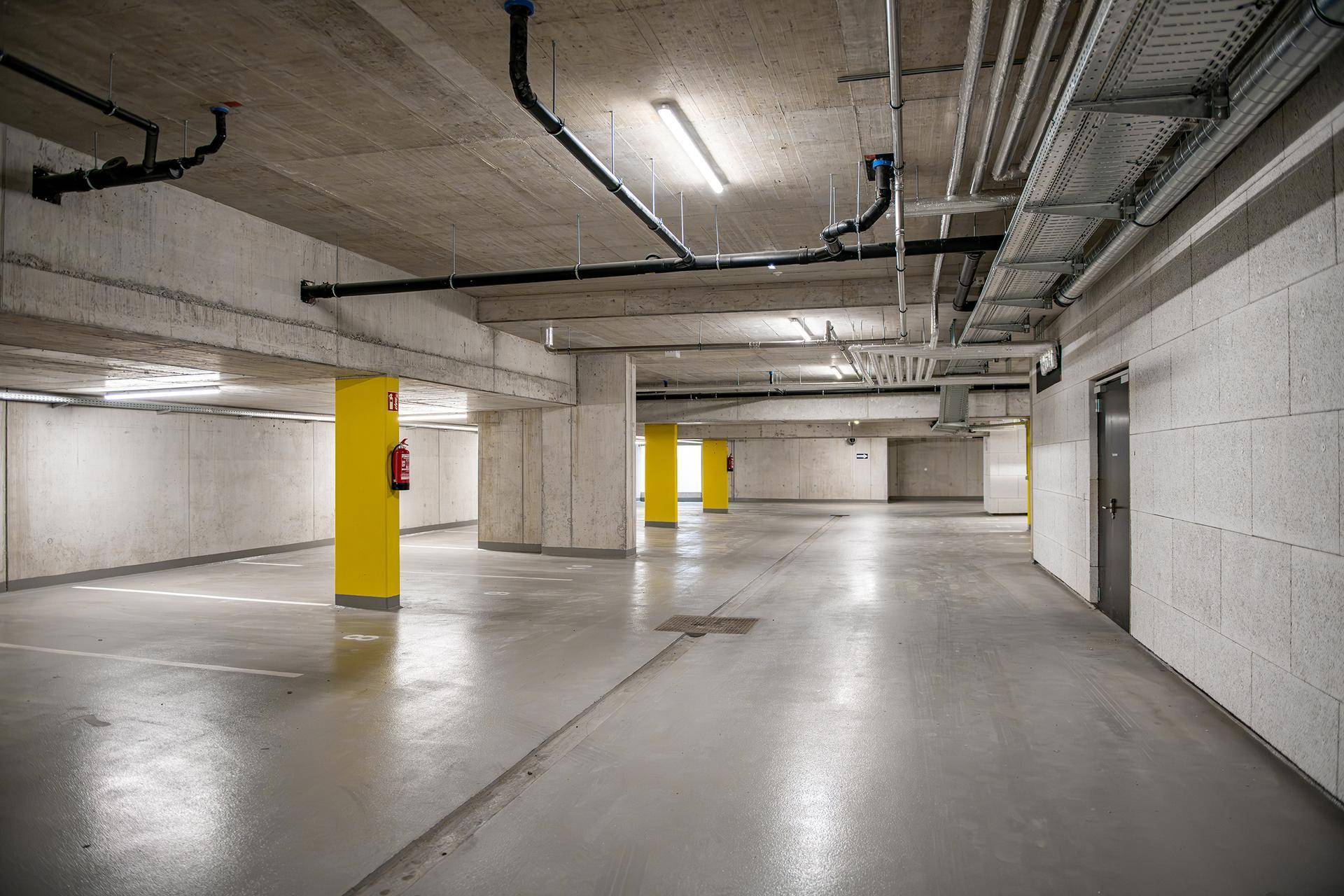 Geräumige Tiefgarage mit Betonwänden und gelben Säulen.