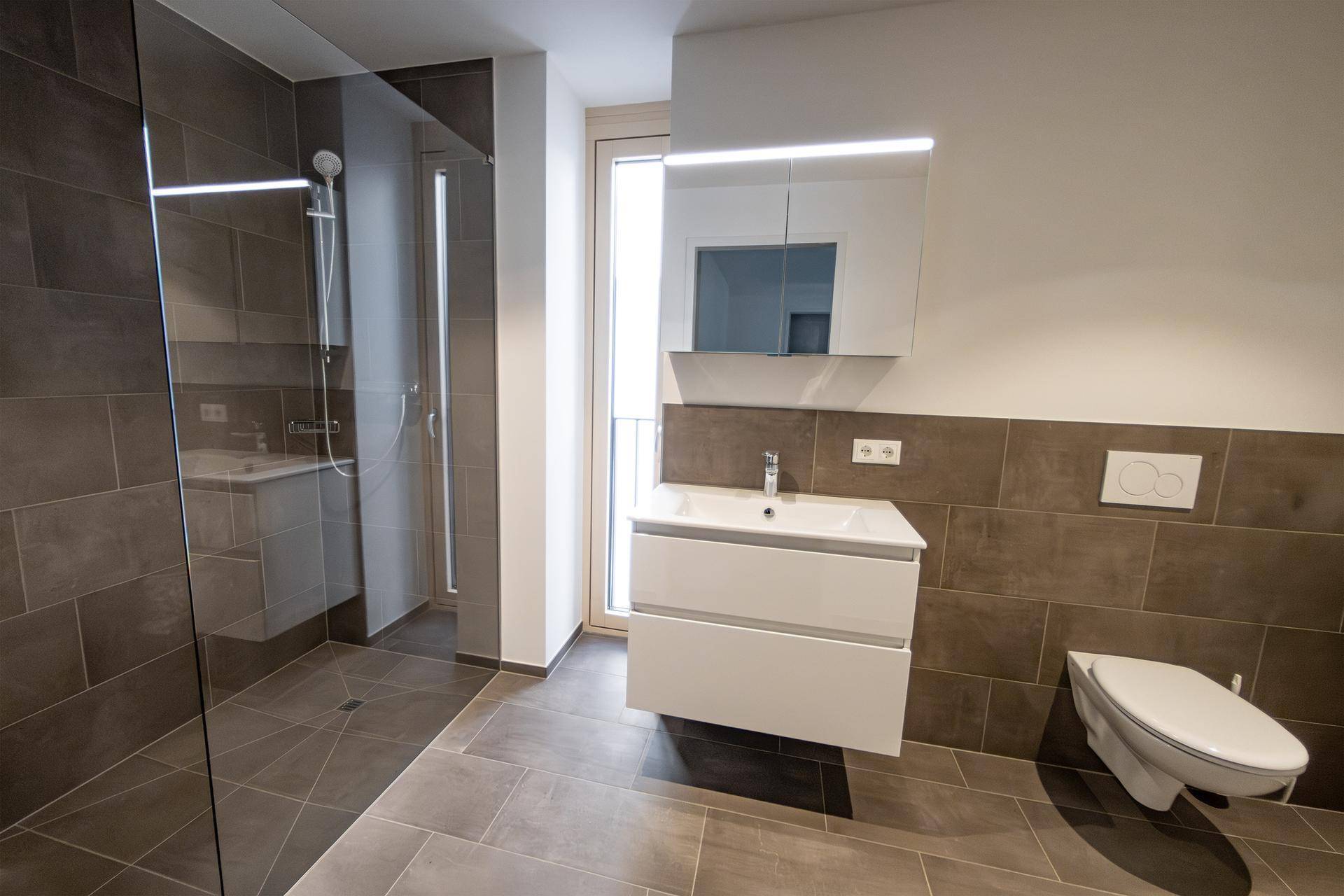 Modernes Badezimmer mit großer begehbarer Dusche, Waschtisch und Wand-WC.