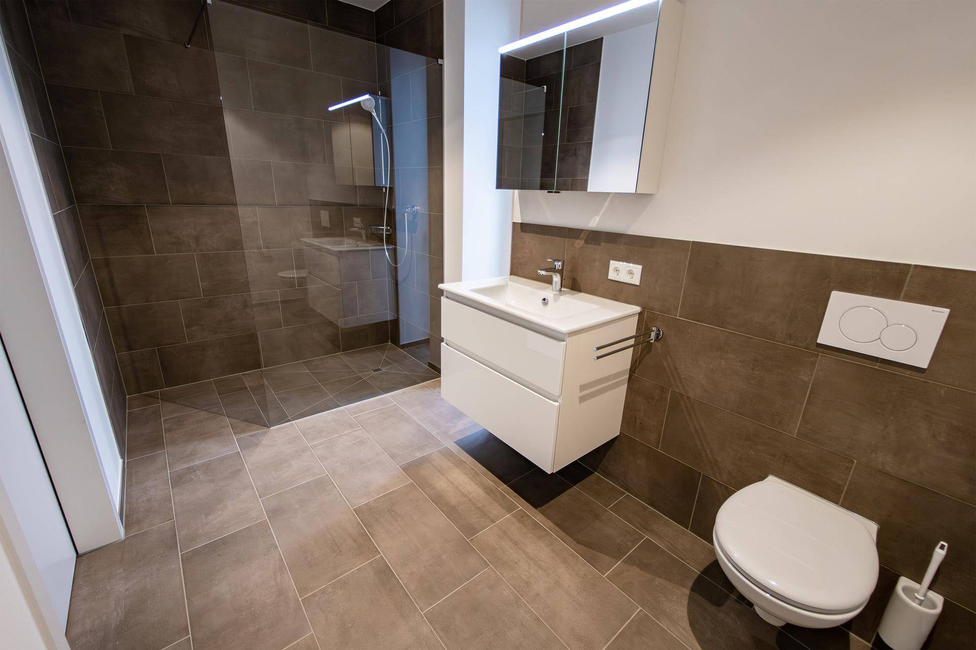 Modernes Badezimmer mit braunen Fliesen, ebenerdiger Dusche und schwebendem Waschtisch.