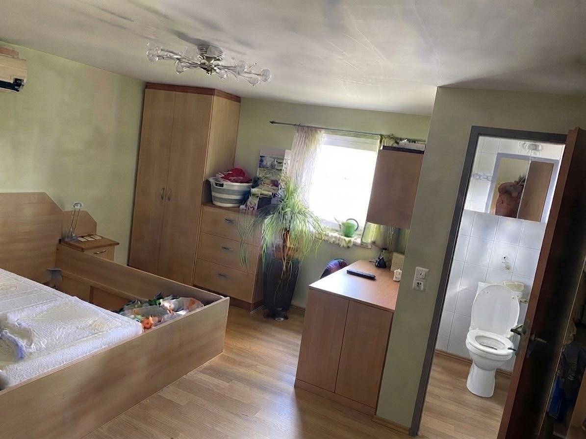 Schlafzimmer mit Holzboden, Kleiderschrank und direktem Zugang zu einem kleinen WC.