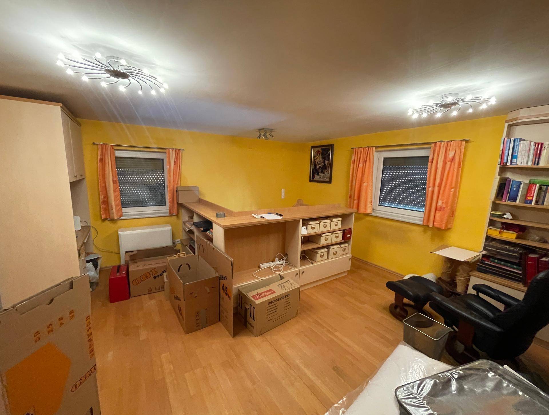 Helles Arbeitszimmer mit gelben Wänden, Schreibtisch und Regalen, bereit zur Einrichtung.