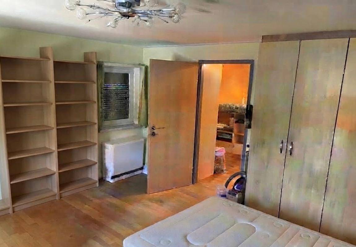 Schlafzimmer mit Holzboden, Bücherregalen und Kleiderschrank, mit Blick in den Flur.