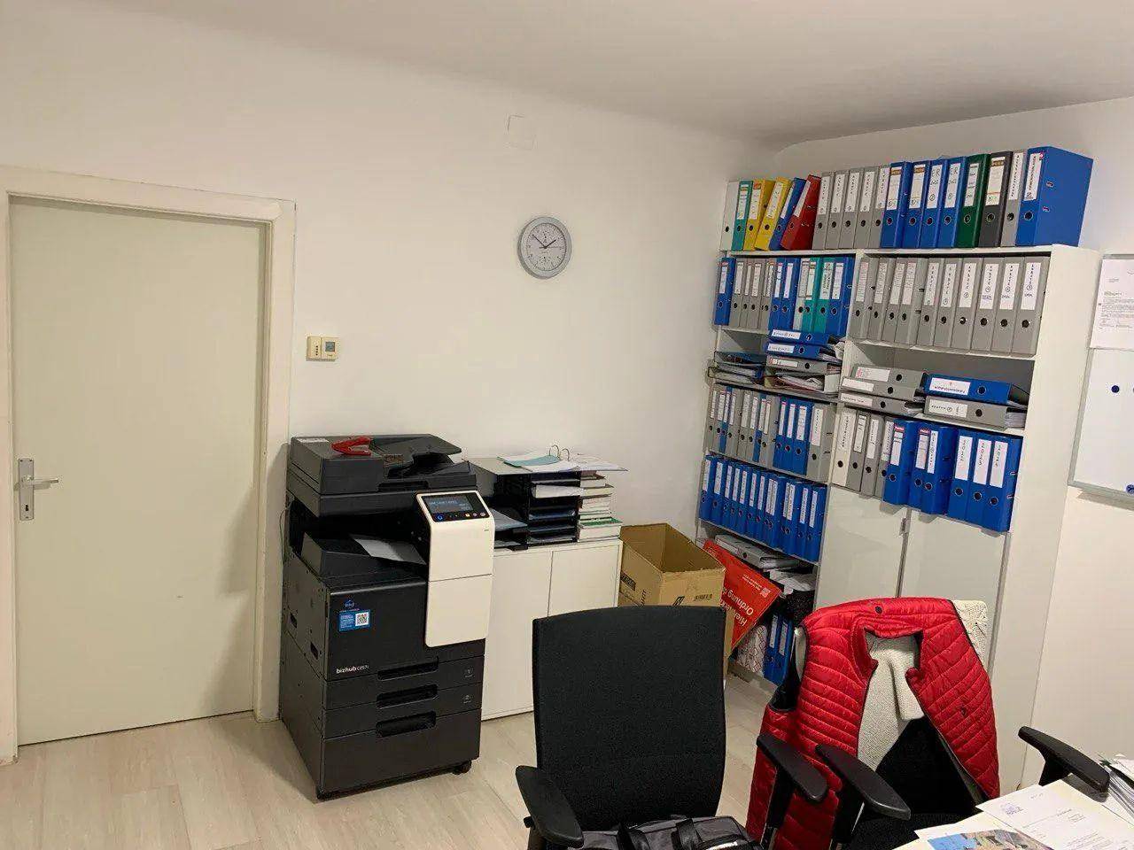 Büroraum mit Aktenschränken, Drucker und einer Tür, gut organisiert für den Arbeitsalltag.