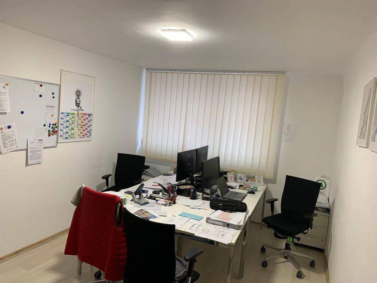Übersicht des Büros mit mehreren Arbeitsplätzen, Whiteboard und natürlichem Lichteinfall.