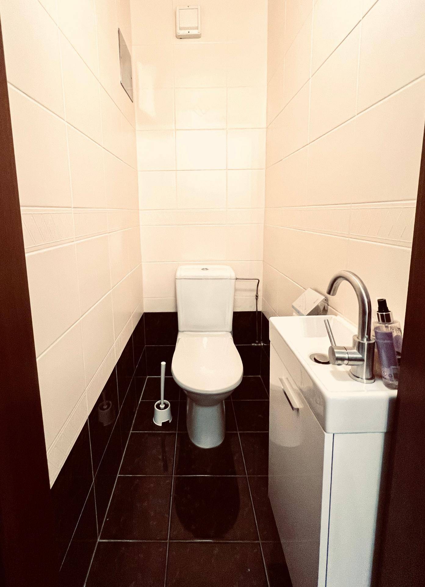 Kleines Gäste-WC mit weißen und schwarzen Fliesen sowie modernem Waschbecken.