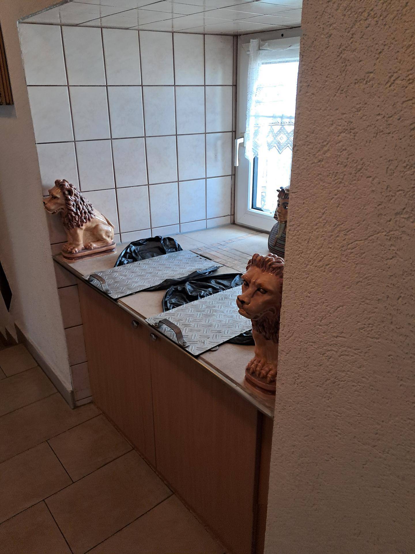 Hauswirtschaftsraum mit einer Arbeitsfläche, gefliesten Wänden und einem Fenster.