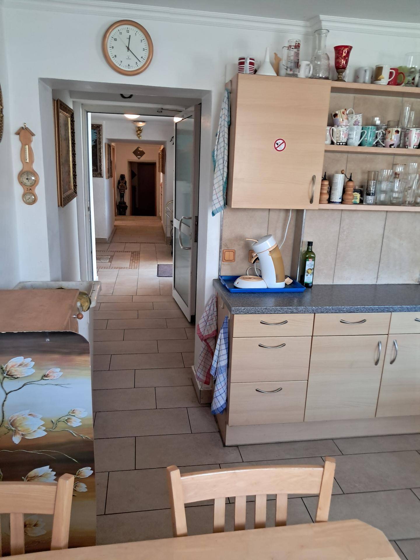 Blick aus der Küche mit Holzmöbeln in den angrenzenden Flur mit Fliesenboden.