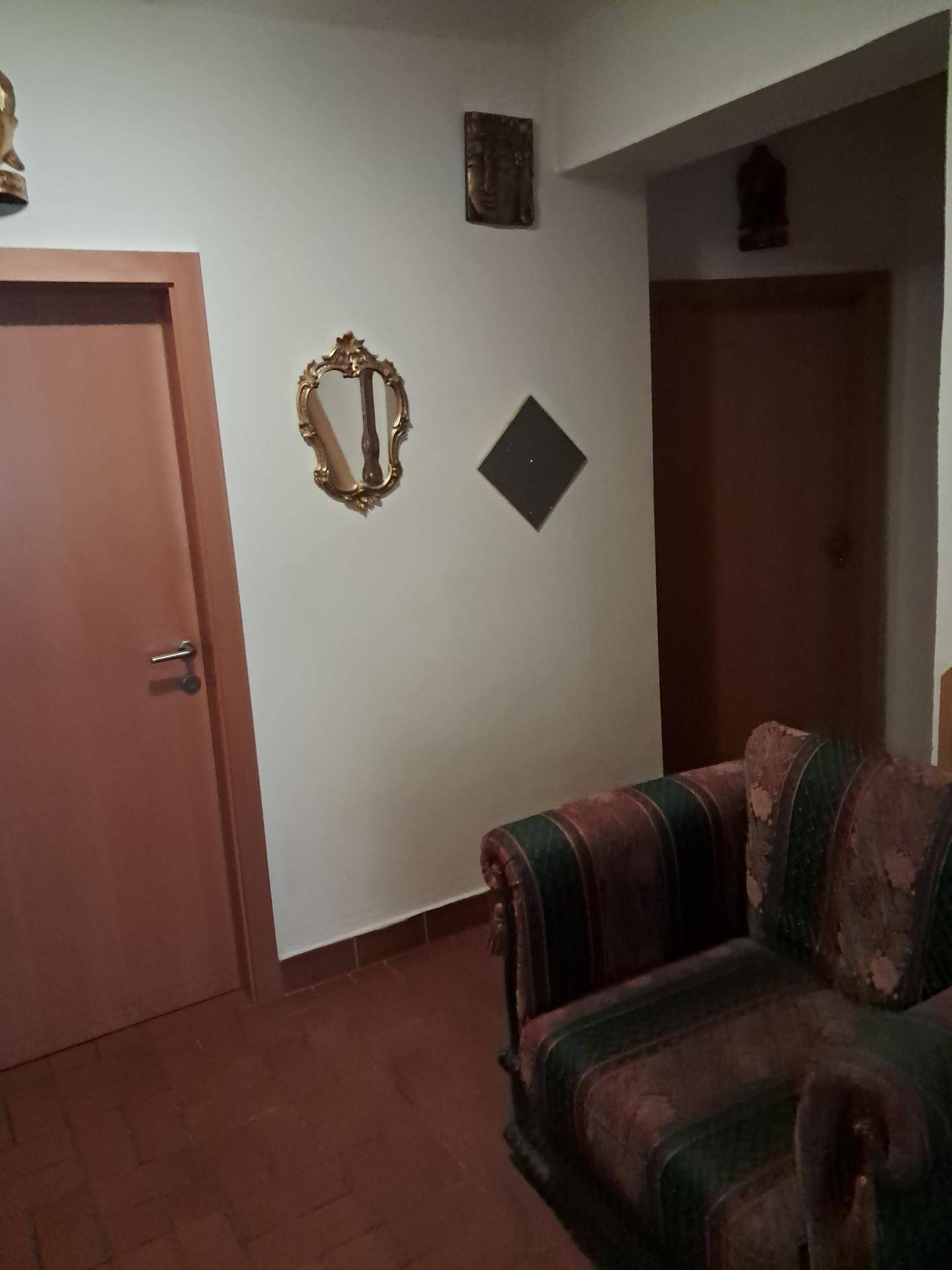 Flurbereich mit einem Sofa, Holztüren und Terrakotta-Fliesenboden.