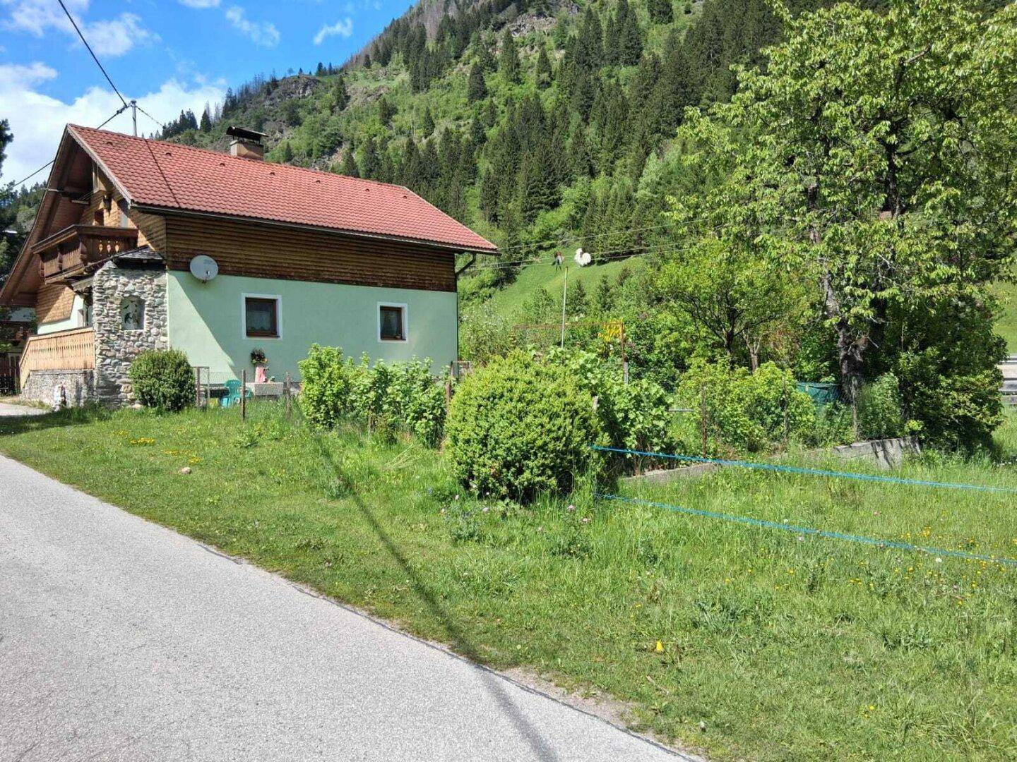 Rückseite eines traditionellen Hauses mit Gartenbereich und Blick auf die Berge.