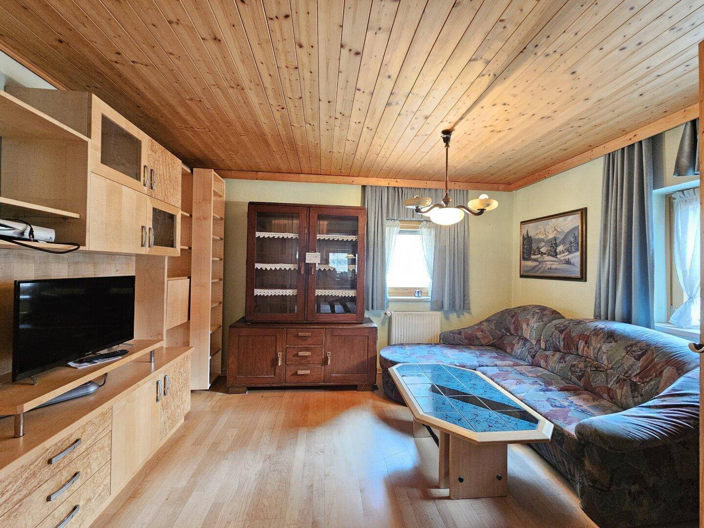 Gemütliches Wohnzimmer mit Holzdecke, Parkettboden und traditionellen Möbeln.