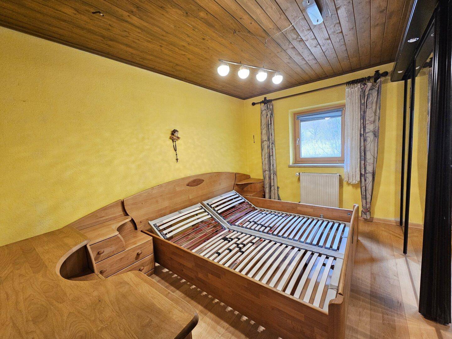 Schlafzimmer mit Holzdecke, Parkettboden und traditionellem Holzbett.