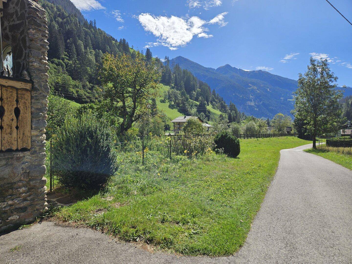 Malerische Landschaft mit grünen Wiesen und Bergen, umgeben von üppiger Natur.