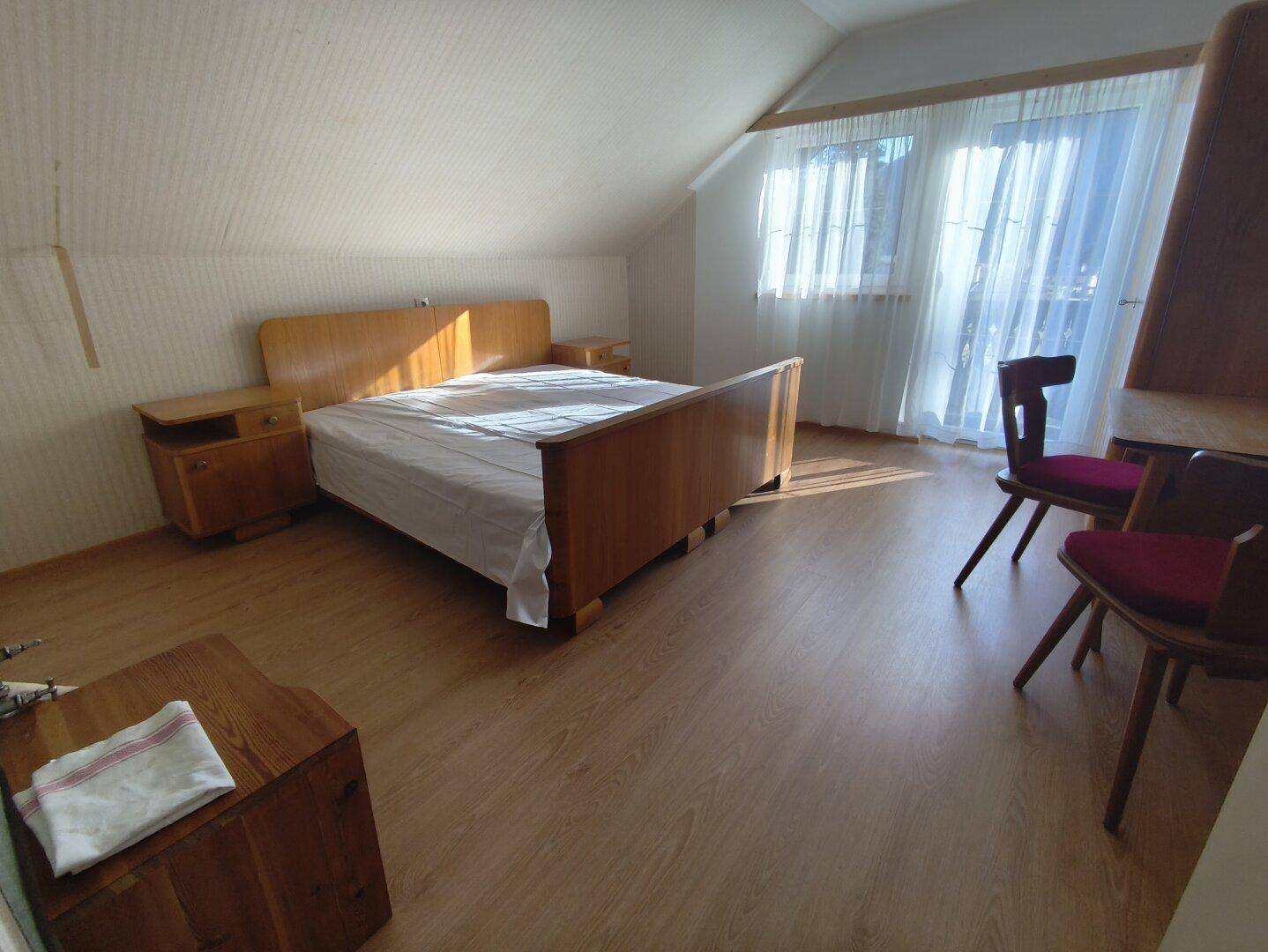 Geräumiges Schlafzimmer im Dachgeschoss mit Holzbett, Nachttischen und schrägen Decken.