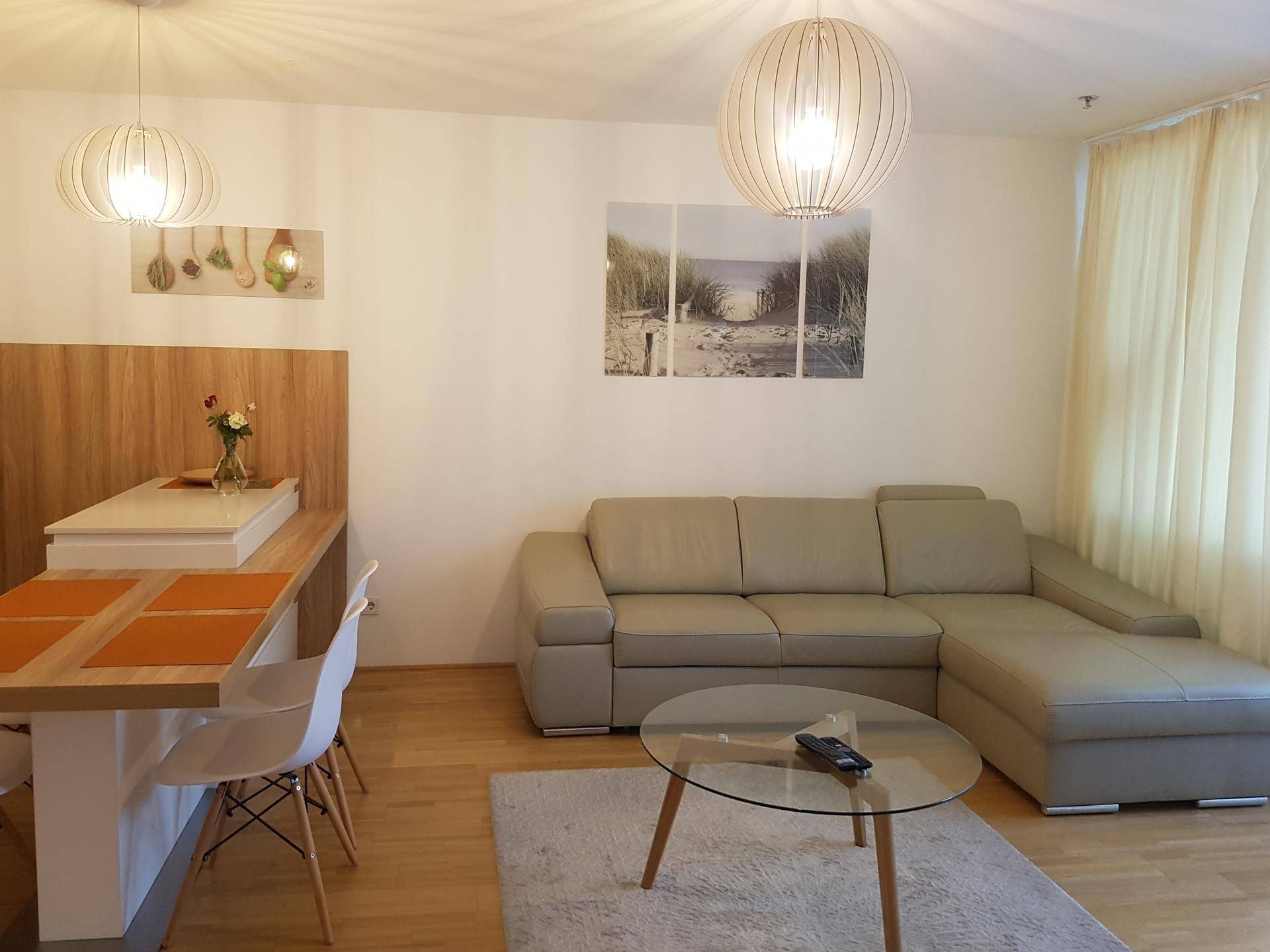 Offener Wohn- und Essbereich mit bequemem Sofa, modernem Esstisch und Holzboden.