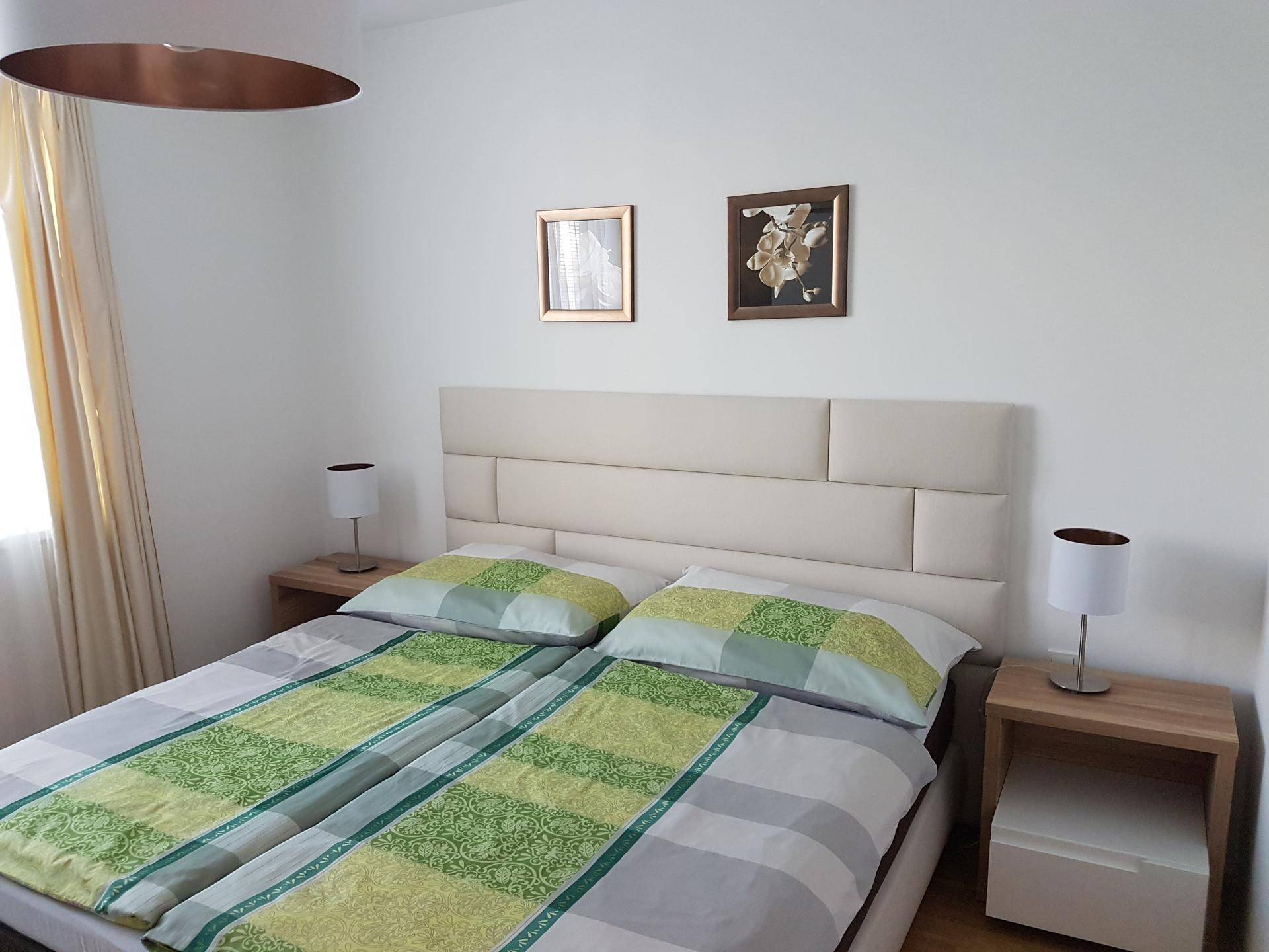 Gemütliches Schlafzimmer mit zwei Einzelbetten, Nachttischen und schlichter Wanddekoration.