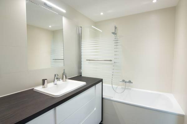 Modernes Badezimmer mit Badewanne, Duschabtrennung und einem einzelnen Waschbecken.