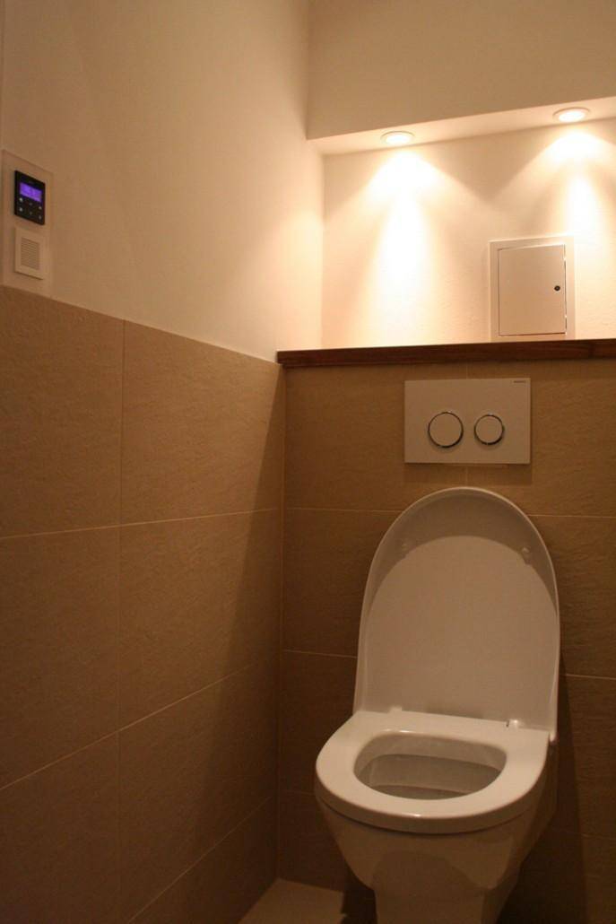 Modernes Gäste-WC mit Wand-WC, Fliesen und integrierter Beleuchtung, funktional und sauber.