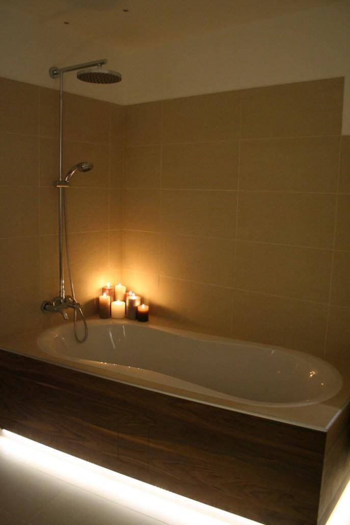 Modernes Badezimmer mit Badewanne, Regendusche und stimmungsvoller Kerzenbeleuchtung für Entspannung.