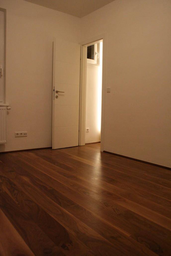 Geräumiges Schlafzimmer mit Holzparkettboden und weißer Tür, bietet vielseitige Gestaltungsmöglichkeiten.