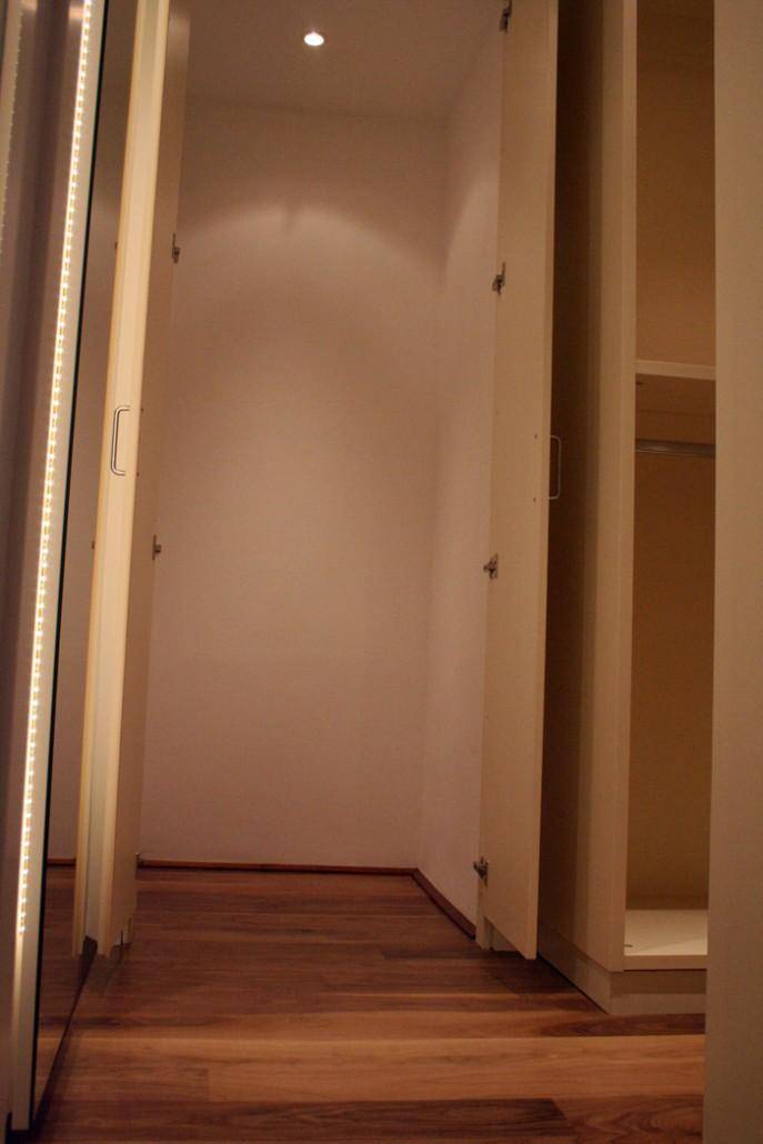 Begehbarer Kleiderschrank mit Holzparkettboden und integrierter Beleuchtung, bietet viel Platz.