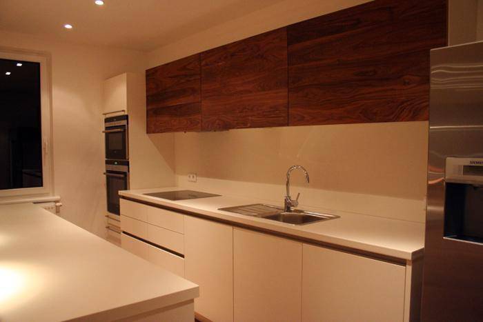 Helle Küche mit Spülbecken, Kochfeld und eleganten Holzschränken über der Arbeitsplatte.