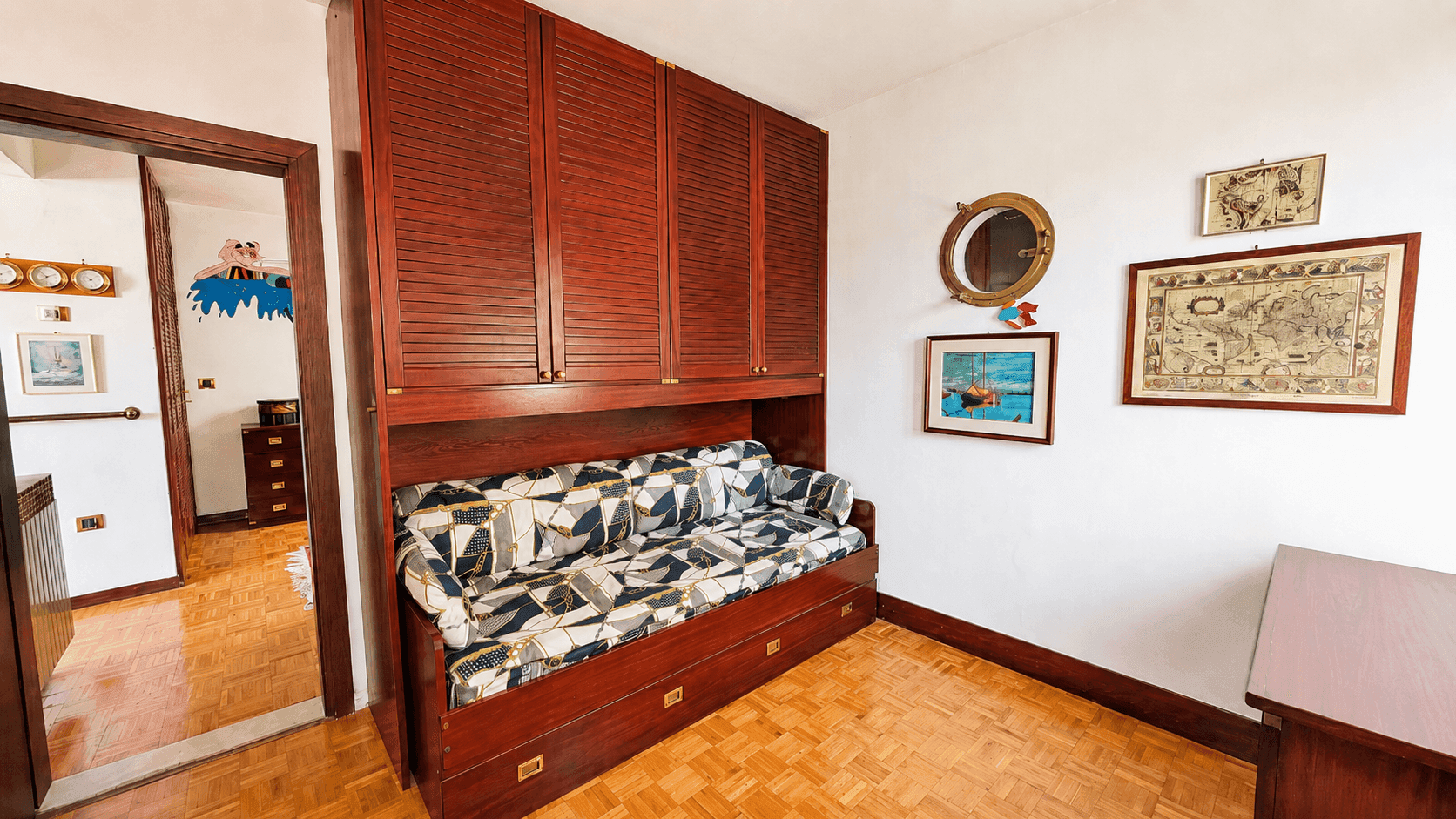 Gemütliches Schlafzimmer mit Holzparkett, integriertem Schrankbett und maritimer Dekoration.