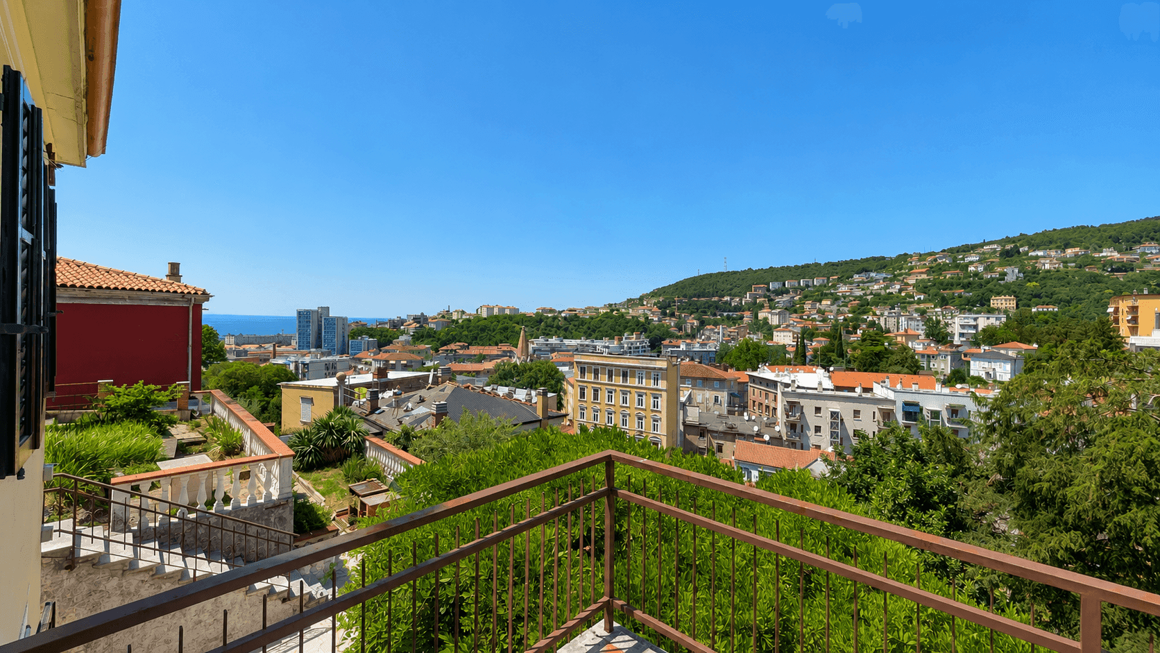 Balkon mit Metallgeländer und weitem Blick auf die Stadt und die umliegende Landschaft.