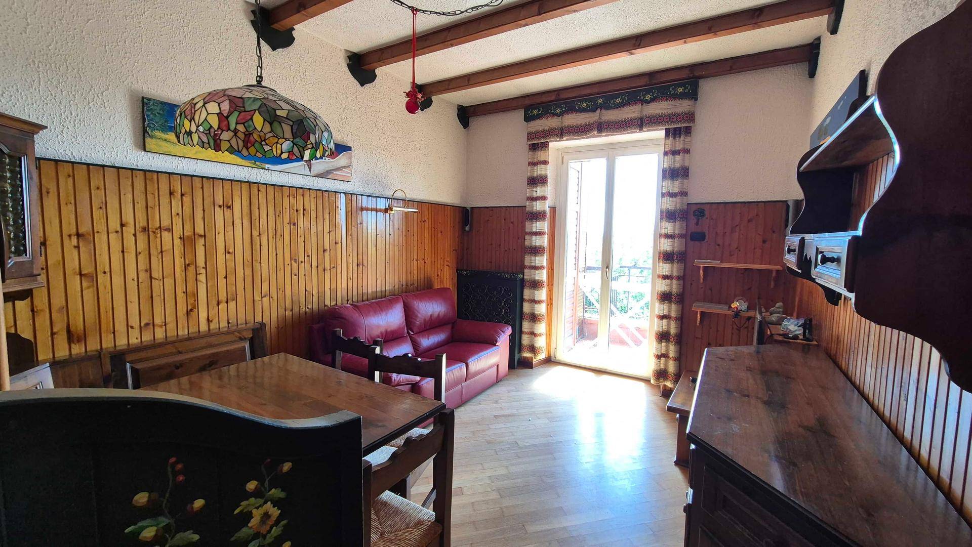 Helles Wohnzimmer mit Holzvertäfelung, Holzbalken und direktem Zugang zu einem Balkon.