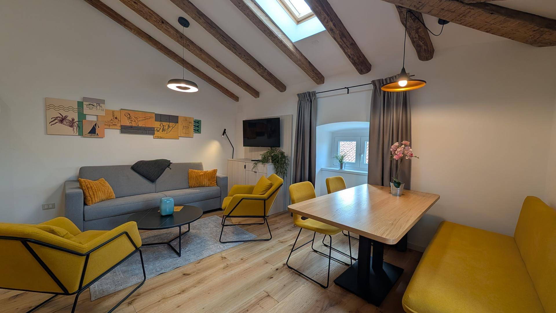 Geräumiger Wohn- und Essbereich mit Holzbalken, Dachfenstern und gemütlicher Einrichtung.
