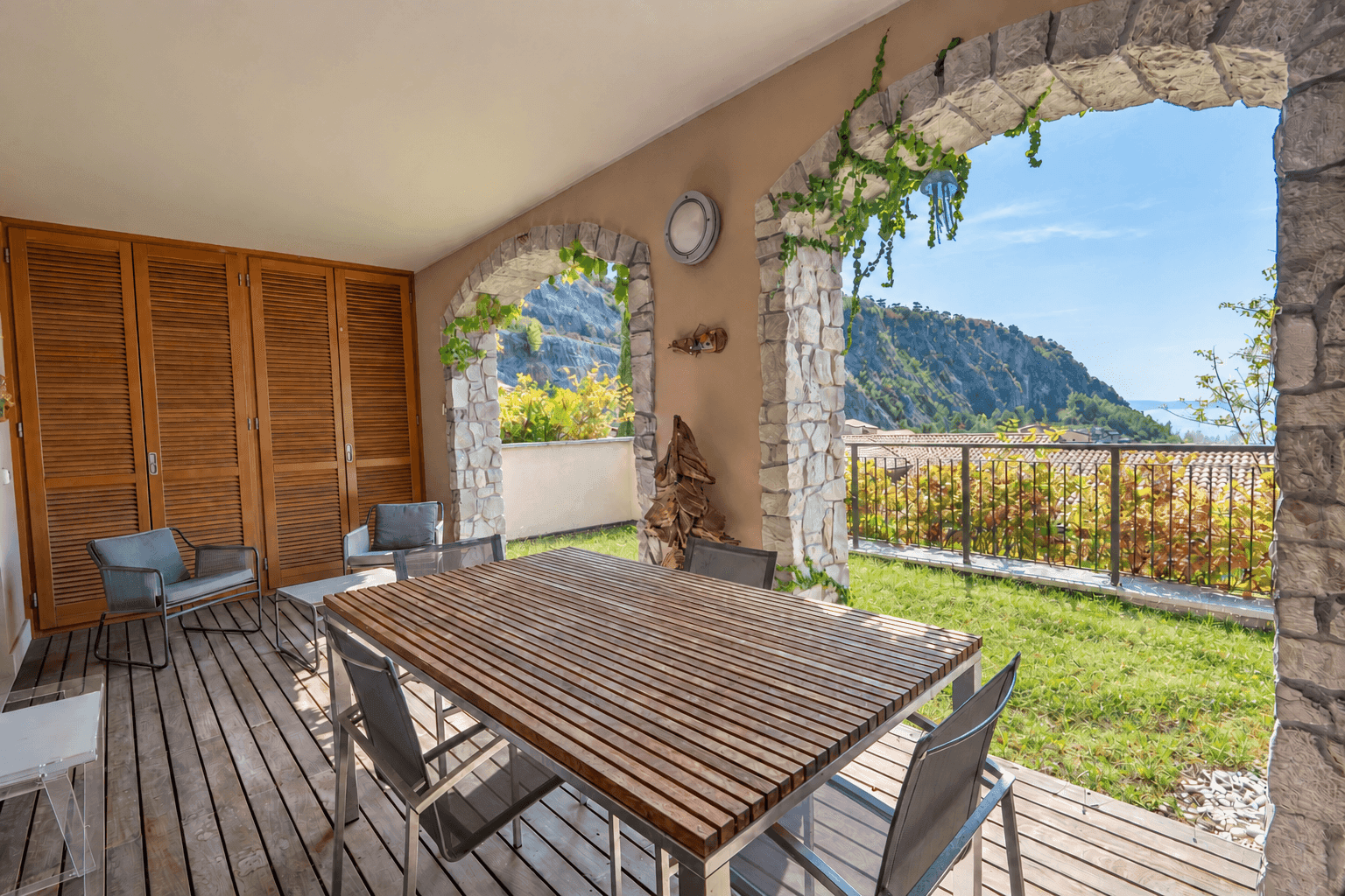 Geräumige überdachte Terrasse mit großem Esstisch, Holzboden und malerischem Meerblick.