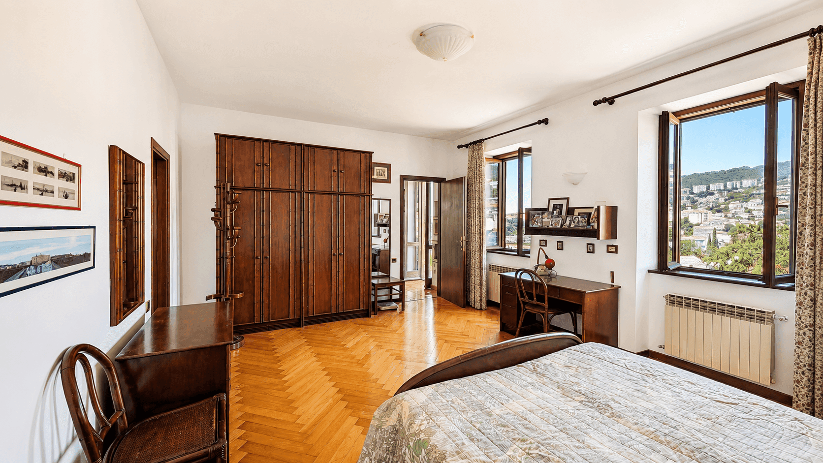 Geräumiges Schlafzimmer mit Holzparkett, großem Kleiderschrank und Schreibtisch, bietet einen weiten Blick.