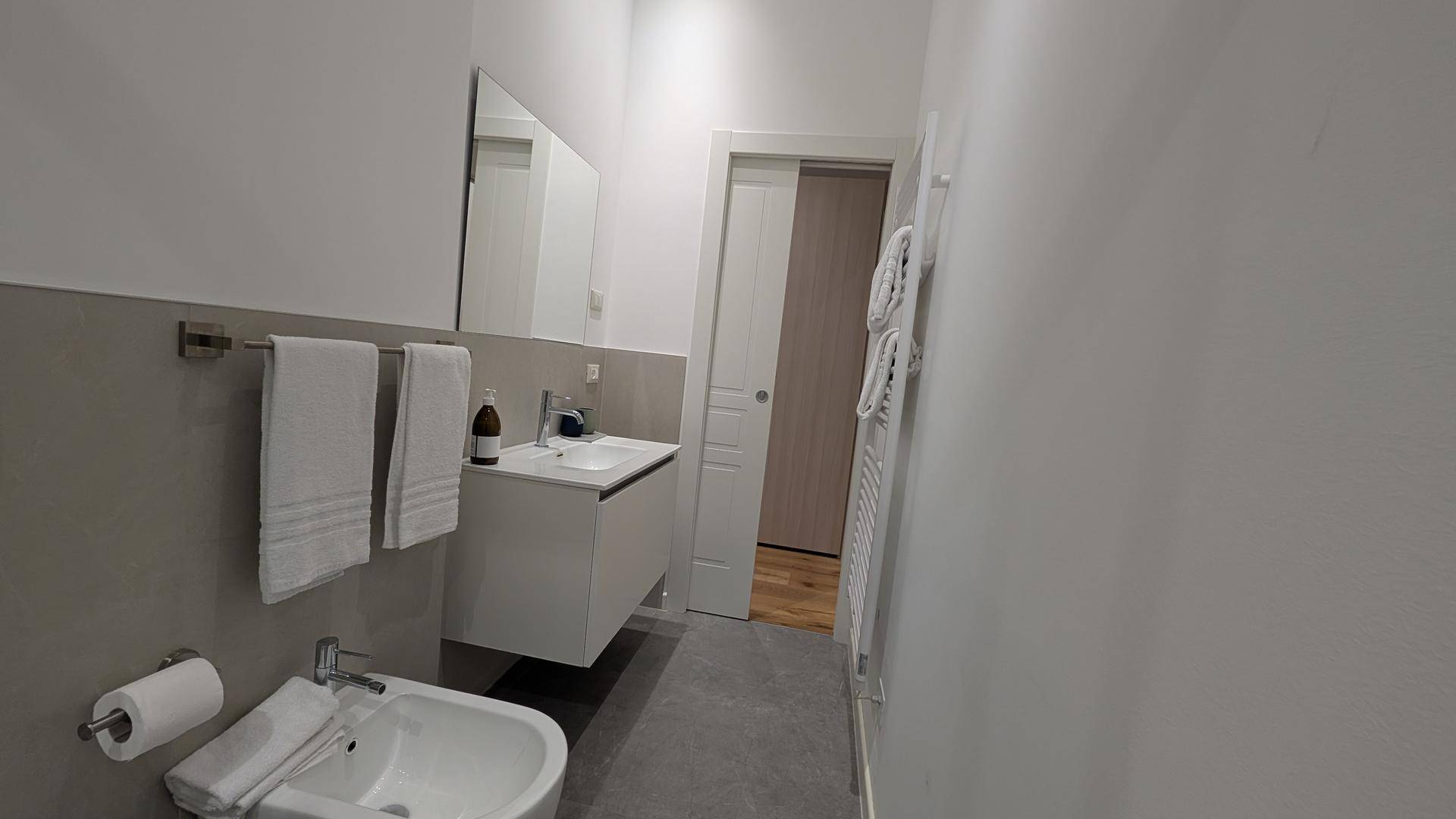 Modernes Badezimmer mit schwebendem Waschtisch, Spiegel und beheiztem Handtuchhalter.