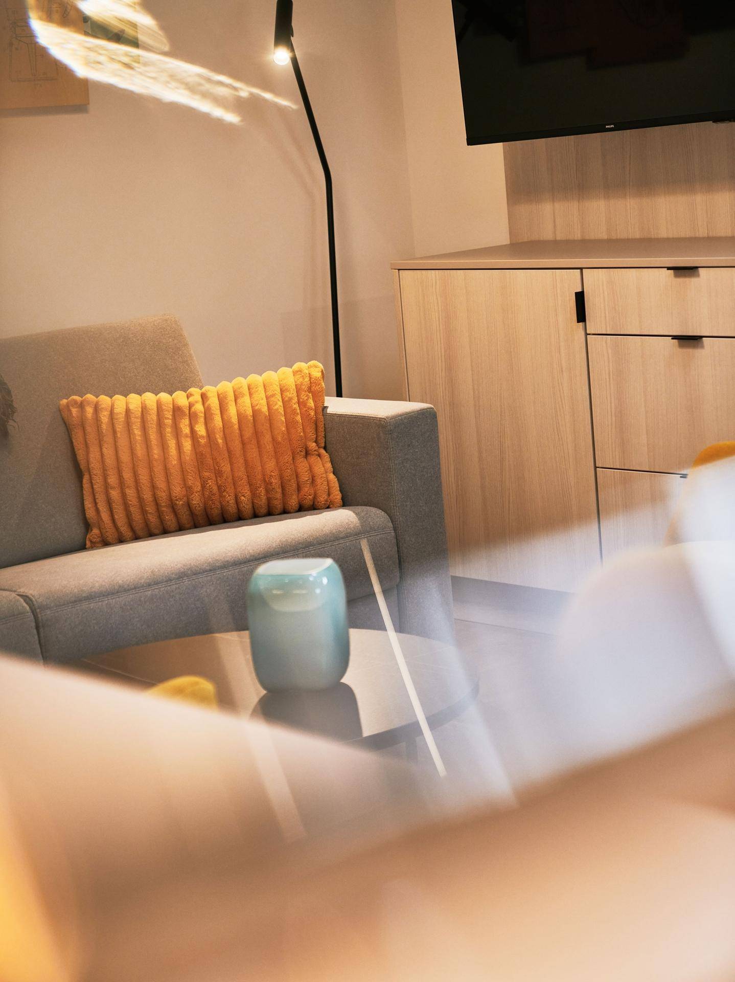Gemütliche Sitzecke mit grauem Sofa, orangefarbenem Kissen und Beistelltisch in einem modernen Ambiente.
