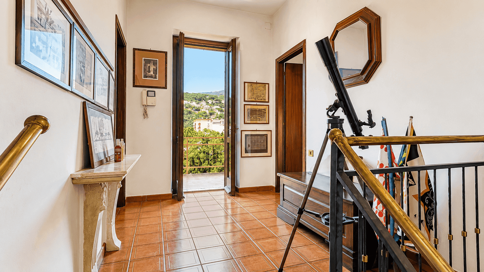 Heller Flur im Obergeschoss mit Terrakottafliesen, Treppengeländer und Zugang zum Balkon.
