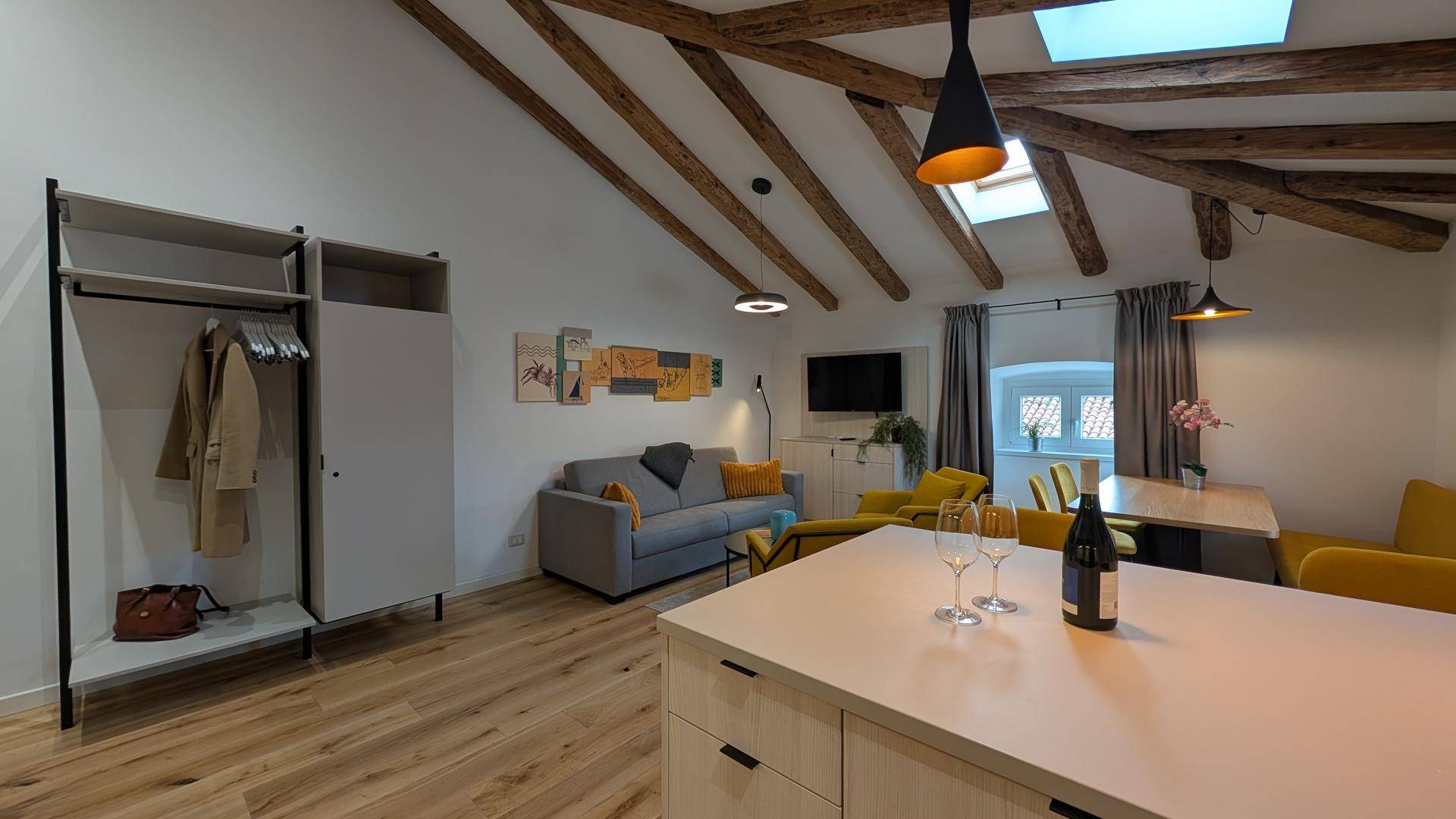 Offener Wohnbereich mit Garderobe, Holzbalken und Blick auf den Essbereich und die Küche.