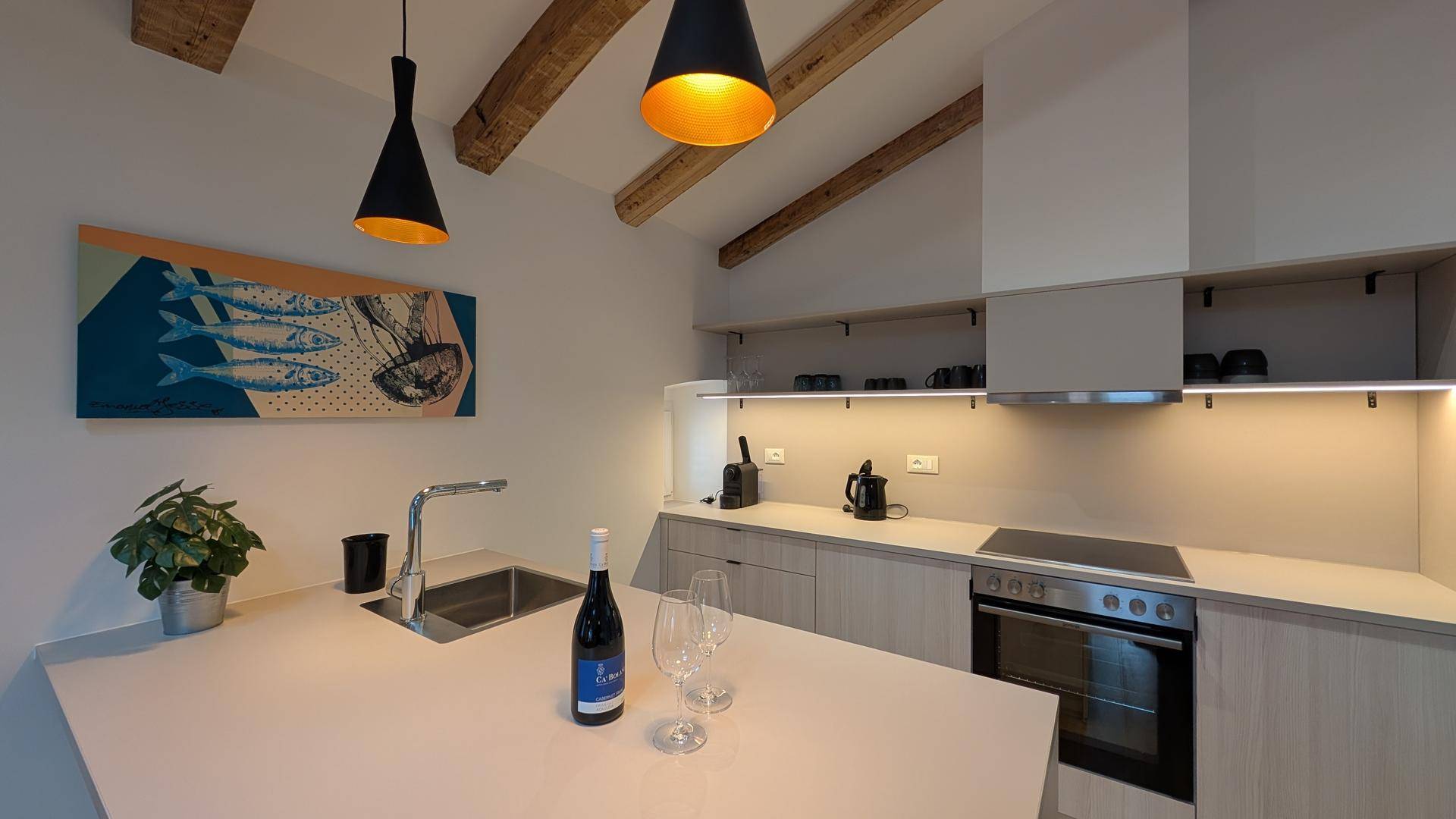 Moderne Küchenzeile mit hellen Holzfronten, Induktionskochfeld und integriertem Backofen.
