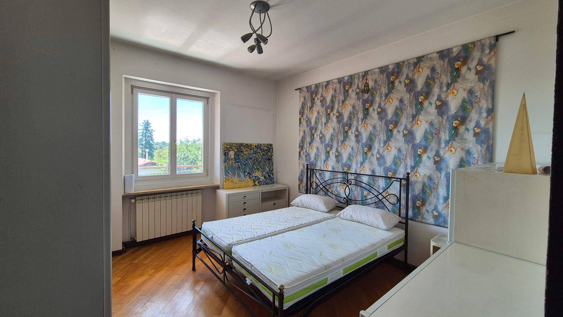 Schlafzimmer mit zwei Einzelbetten, Holzfußboden und einem Fenster mit Blick ins Grüne.