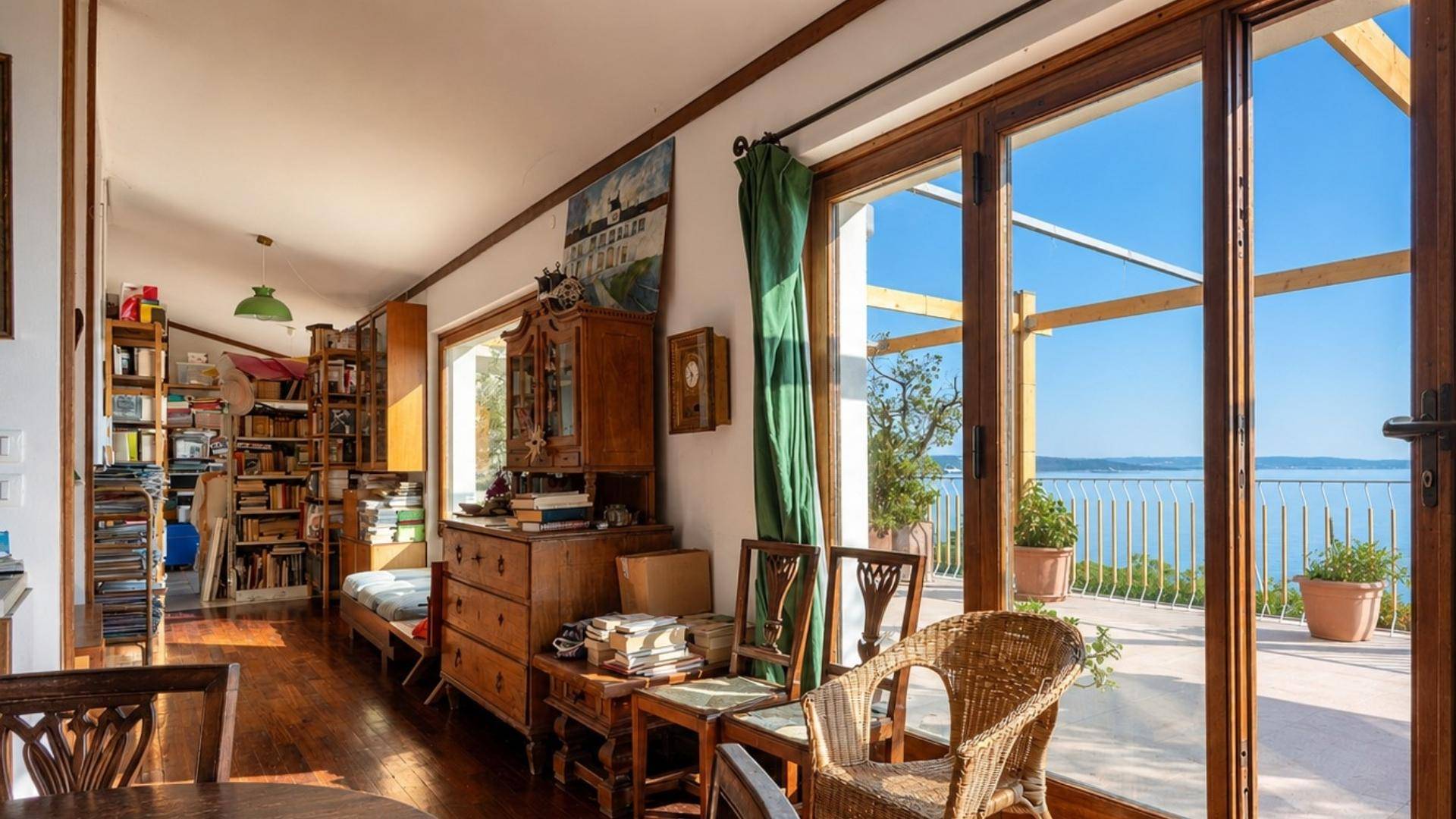 Helles Wohnzimmer mit Holzboden, Meerblick und Zugang zur Terrasse durch große Glastüren.