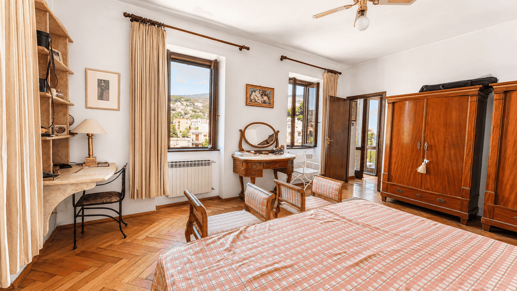 Geräumiges Schlafzimmer mit Parkettboden, Schminktisch und Fenstern mit Stadtblick.