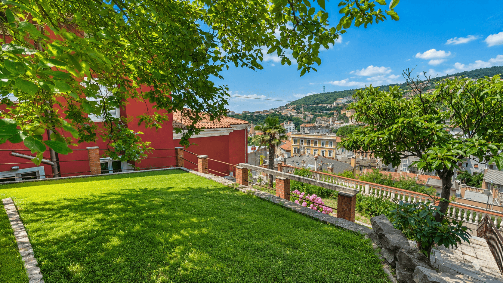 Grüner Garten mit Rasenfläche und weitem Blick auf die Stadt und die umliegenden Hügel.