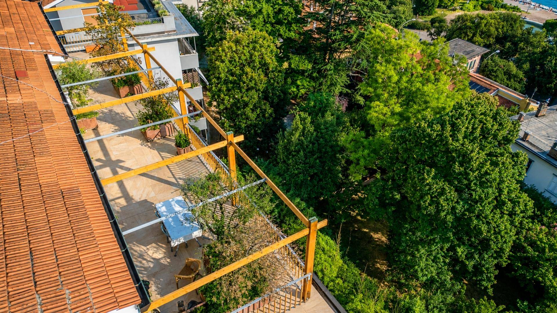 Dachterrasse mit Pergola und Sitzbereich, umgeben von üppigem Grün und angrenzenden Dächern.