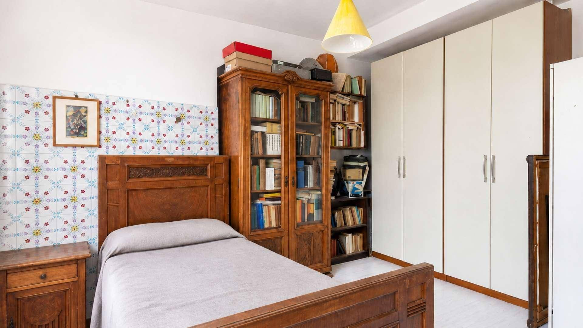 Schlafzimmer mit Holzbett, Bücherregal und weißem Kleiderschrank unter Dachschrägen.