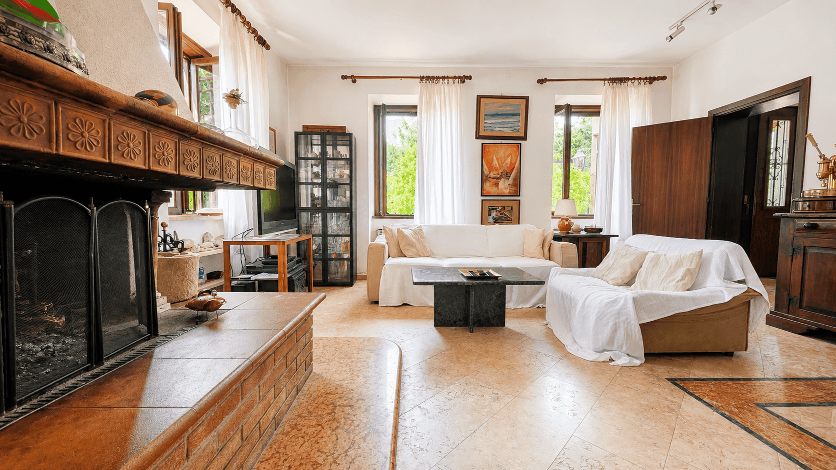Großzügiges Wohnzimmer mit Kamin, Terrakottafliesen und Zugang zu weiteren Räumen.