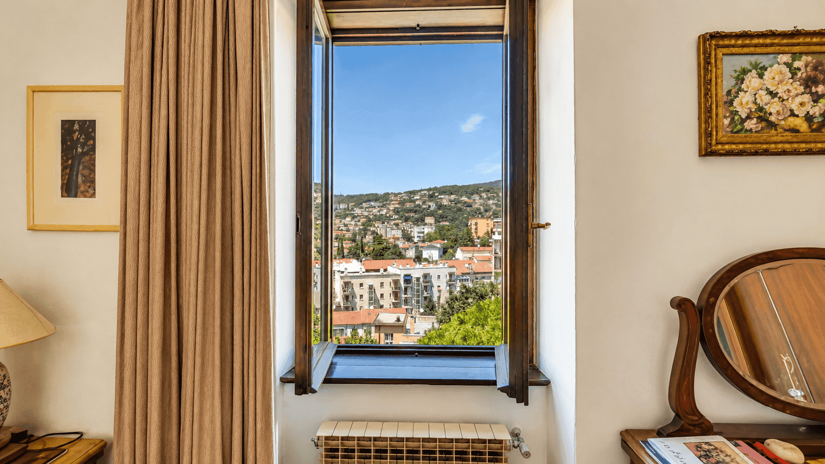 Fenster im Schlafzimmer mit Blick auf die Stadt und die grünen Hügel, das viel Tageslicht hereinlässt.